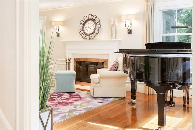 living area featuring a glass covered fireplace, wood finished floors, and ornamental molding