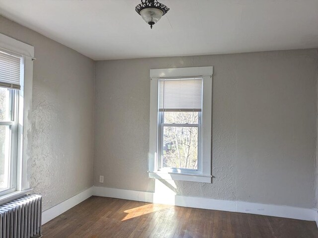 12-14 Essex St, Dover, NH 03820 - empty room with radiator, healthy amount of natural light, wood finished floors, and a textured wall