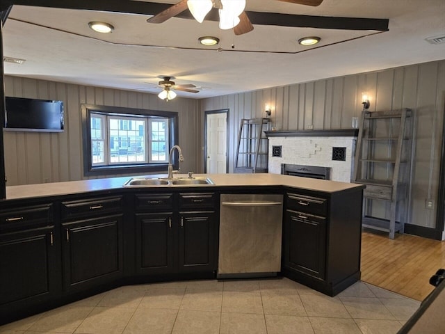 kitchen with kitchen peninsula, sink, stainless steel dishwasher, a fireplace, and light hardwood / wood-style flooring