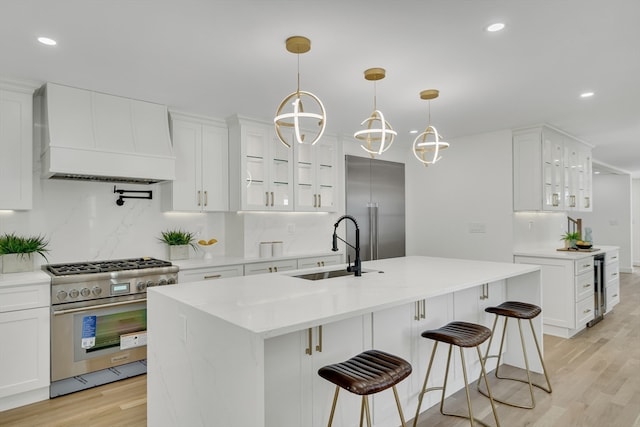 kitchen with custom exhaust hood, white cabinetry, light hardwood / wood-style flooring, a chandelier, and premium appliances