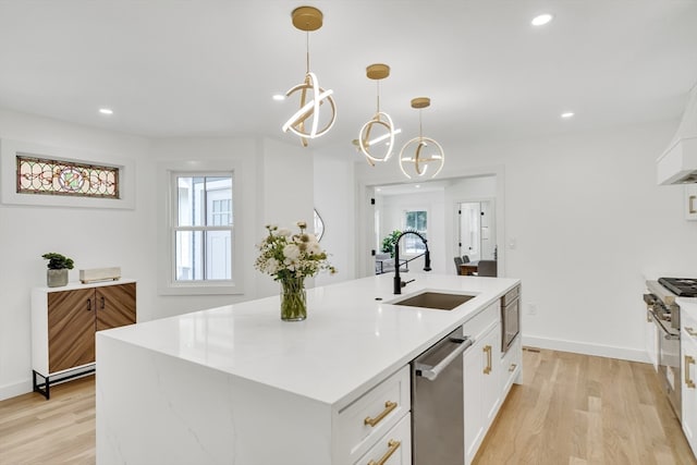 kitchen featuring decorative light fixtures, light hardwood / wood-style floors, a chandelier, sink, and an island with sink