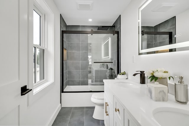 full bathroom featuring tile patterned flooring, toilet, bath / shower combo with glass door, and vanity