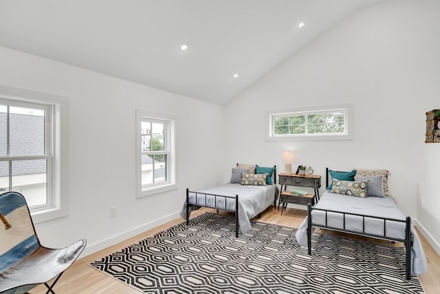 bedroom featuring high vaulted ceiling, wood-type flooring, and multiple windows