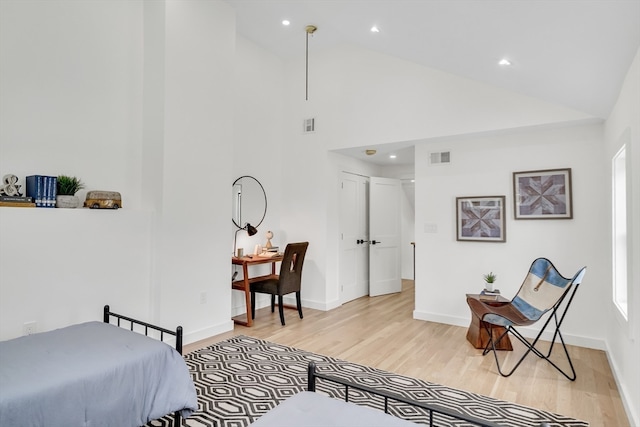 bedroom featuring high vaulted ceiling and light hardwood / wood-style flooring