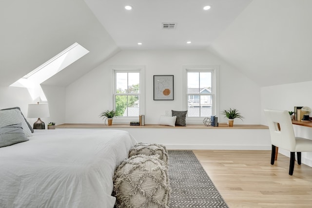 bedroom with light wood-type flooring, multiple windows, and lofted ceiling with skylight