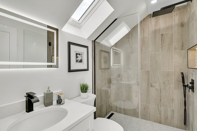 bathroom with tiled shower, vanity, toilet, and vaulted ceiling with skylight