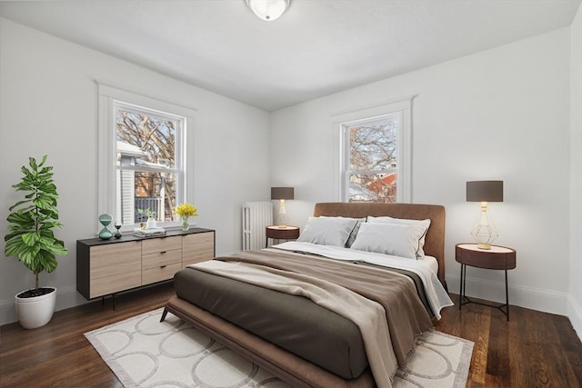 bedroom with multiple windows, dark wood-type flooring, and radiator heating unit