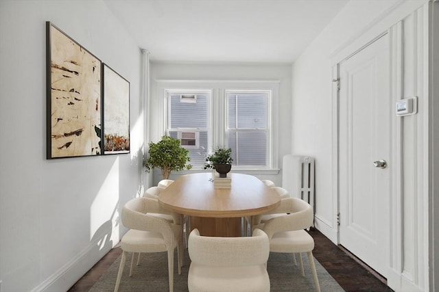 dining area featuring dark wood-type flooring and radiator heating unit