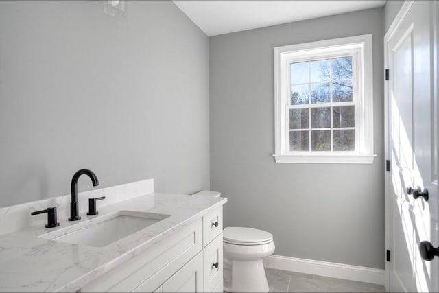 half bathroom featuring tile patterned flooring, toilet, vanity, and baseboards