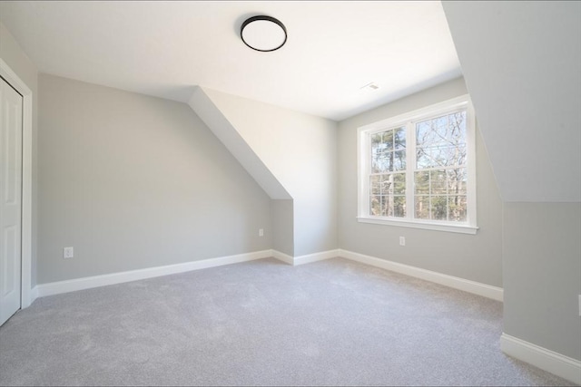 bonus room with light carpet, baseboards, and vaulted ceiling