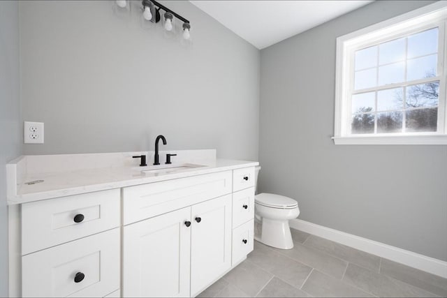 bathroom featuring baseboards, toilet, vanity, and tile patterned flooring