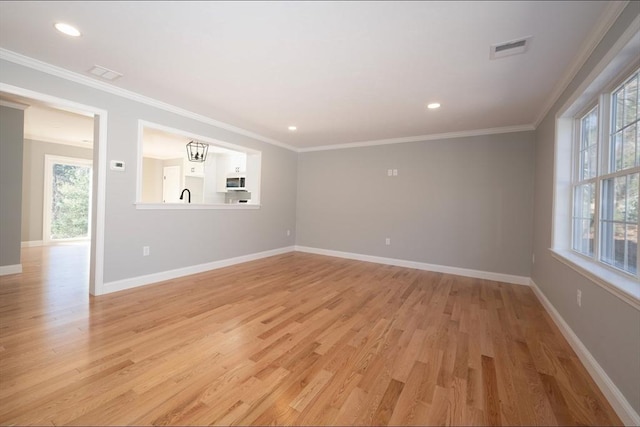 spare room with a wealth of natural light, visible vents, and ornamental molding