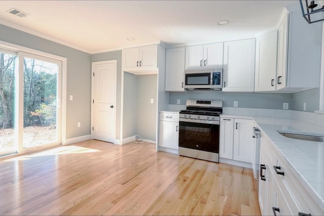 kitchen with visible vents, crown molding, baseboards, light wood-style flooring, and appliances with stainless steel finishes