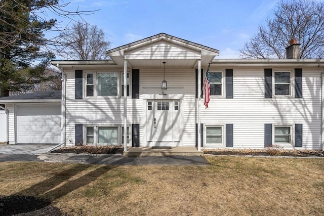 raised ranch featuring a garage, a chimney, a front yard, and aphalt driveway