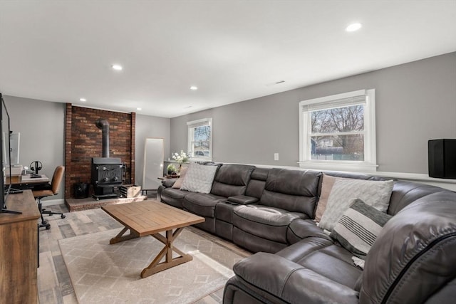 living area with a wealth of natural light, light wood-type flooring, recessed lighting, and a wood stove