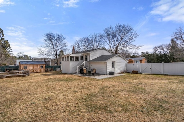 back of property featuring a gate, a shed, a yard, an outdoor structure, and a sunroom