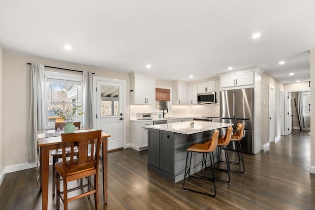 kitchen featuring a sink, a kitchen island, appliances with stainless steel finishes, white cabinets, and decorative backsplash