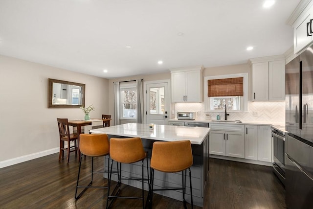 kitchen with dark wood-type flooring, high quality fridge, tasteful backsplash, and a sink