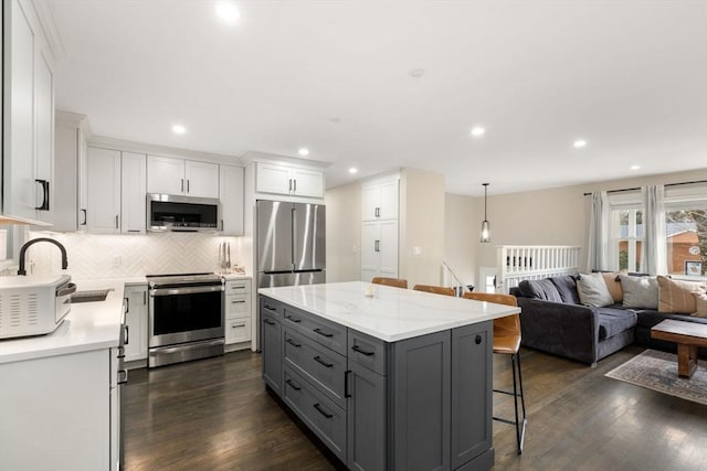 kitchen featuring a breakfast bar area, gray cabinets, stainless steel appliances, white cabinetry, and dark wood-style flooring