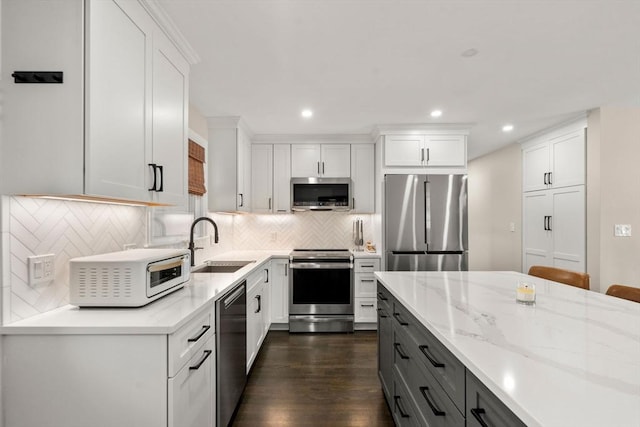 kitchen featuring recessed lighting, a sink, stainless steel appliances, white cabinets, and backsplash