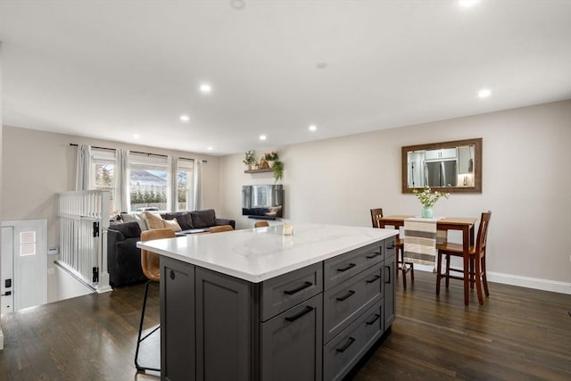 kitchen featuring a kitchen island, dark wood-type flooring, gray cabinetry, and stainless steel refrigerator