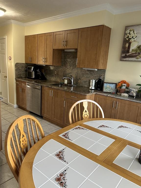 38 Bay Pointe Dr Unit 38, Wareham, MA 02532 - kitchen with dishwasher, backsplash, ornamental molding, light tile patterned flooring, and brown cabinets