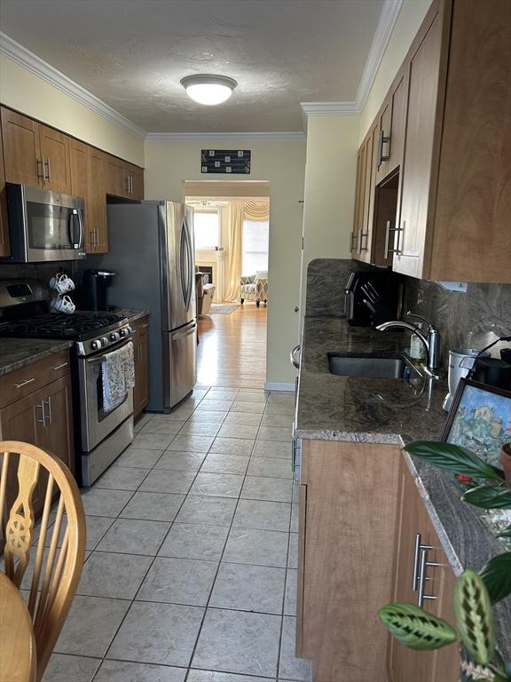 38 Bay Pointe Dr Unit 38, Wareham, MA 02532 - kitchen featuring appliances with stainless steel finishes, light tile patterned floors, crown molding, and dark stone counters