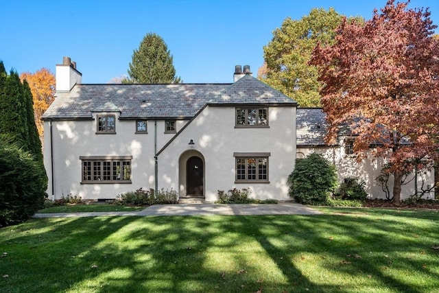 view of front of home with a high end roof, a chimney, and a front yard