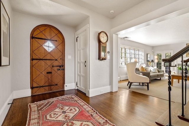 foyer entrance featuring wood finished floors, visible vents, and baseboards