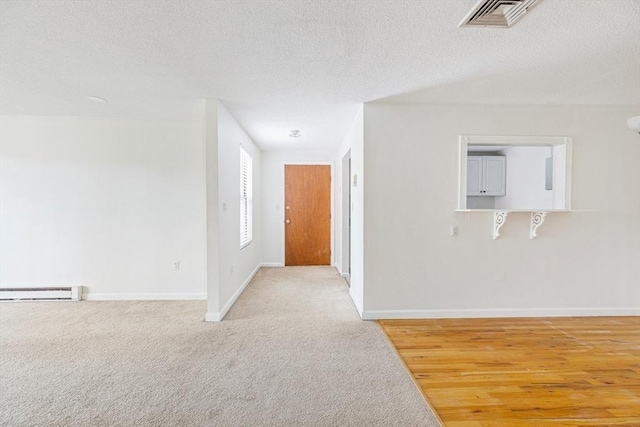 carpeted spare room featuring baseboard heating and a textured ceiling