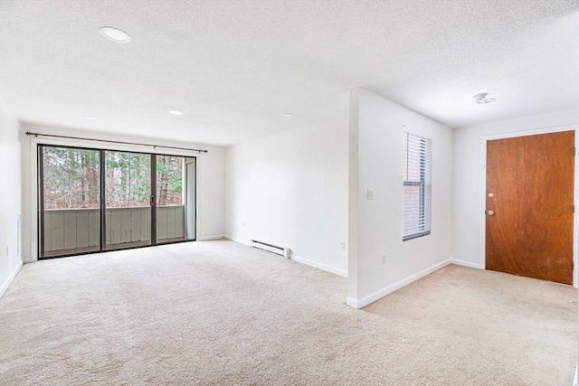 carpeted spare room featuring a textured ceiling and baseboard heating