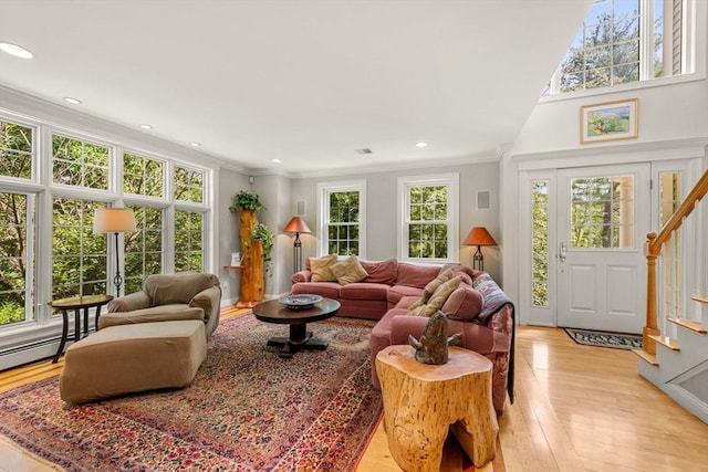 living room with a healthy amount of sunlight, light wood finished floors, stairs, and ornamental molding