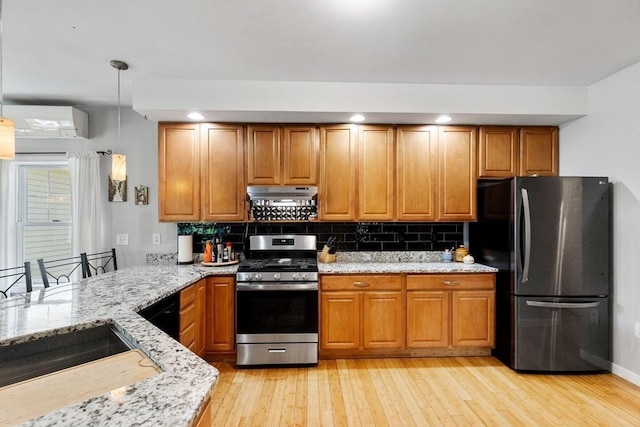 kitchen with stainless steel appliances, a wall unit AC, light wood-style flooring, light stone countertops, and recessed lighting