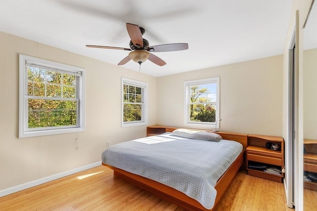 bedroom featuring multiple windows, light wood-type flooring, and baseboards
