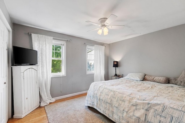 bedroom with light wood-style flooring, baseboards, and ceiling fan