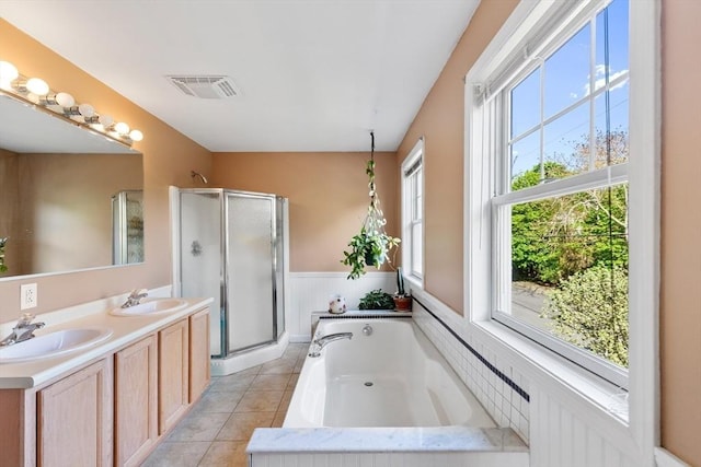 full bathroom featuring a shower stall, a garden tub, double vanity, wainscoting, and tile patterned flooring