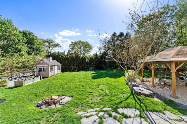 view of grassy yard featuring an outdoor fire pit, a gazebo, and an outdoor structure
