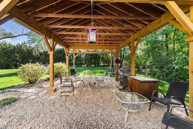 view of patio / terrace featuring area for grilling, a gazebo, and view of wooded area