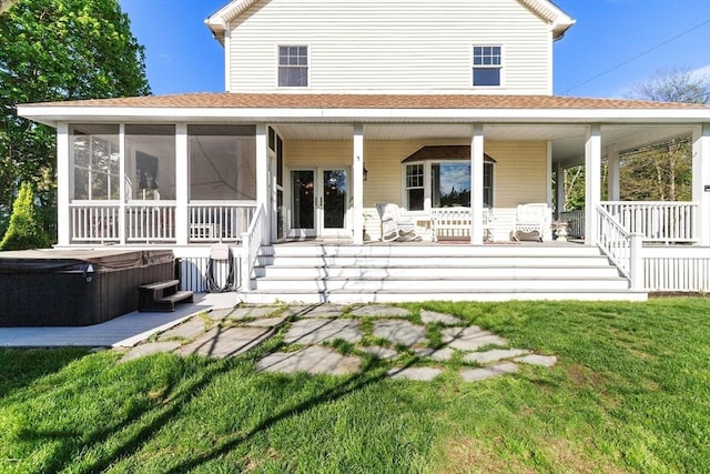 back of property with a hot tub, roof with shingles, a lawn, and covered porch
