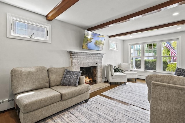 living area featuring a baseboard heating unit, wood finished floors, beamed ceiling, and a fireplace