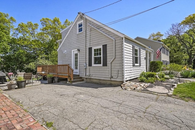 rear view of property featuring a wooden deck and a patio area