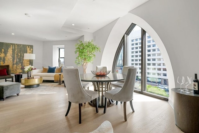 dining area with light wood finished floors, recessed lighting, and arched walkways