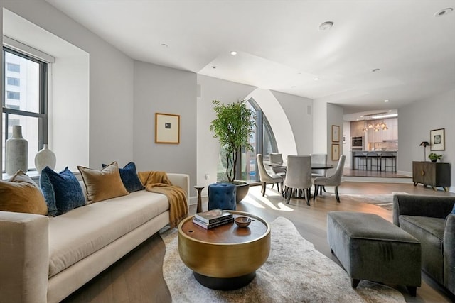 living room featuring recessed lighting, baseboards, arched walkways, and light wood finished floors