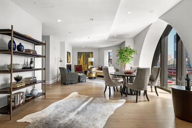 dining room with arched walkways, recessed lighting, baseboards, and wood finished floors