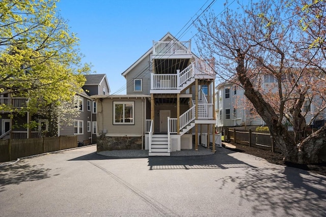 rear view of property featuring stairway, fence, and a balcony