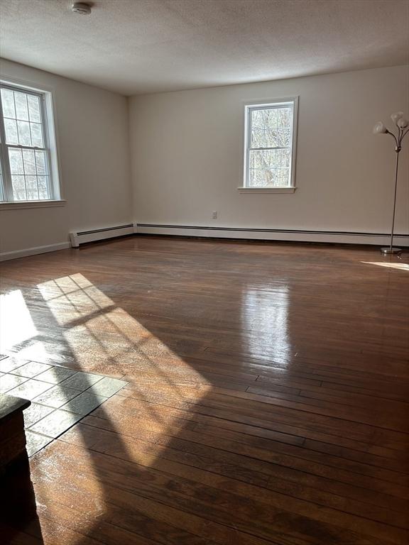 unfurnished room with a textured ceiling, dark hardwood / wood-style flooring, and a baseboard radiator