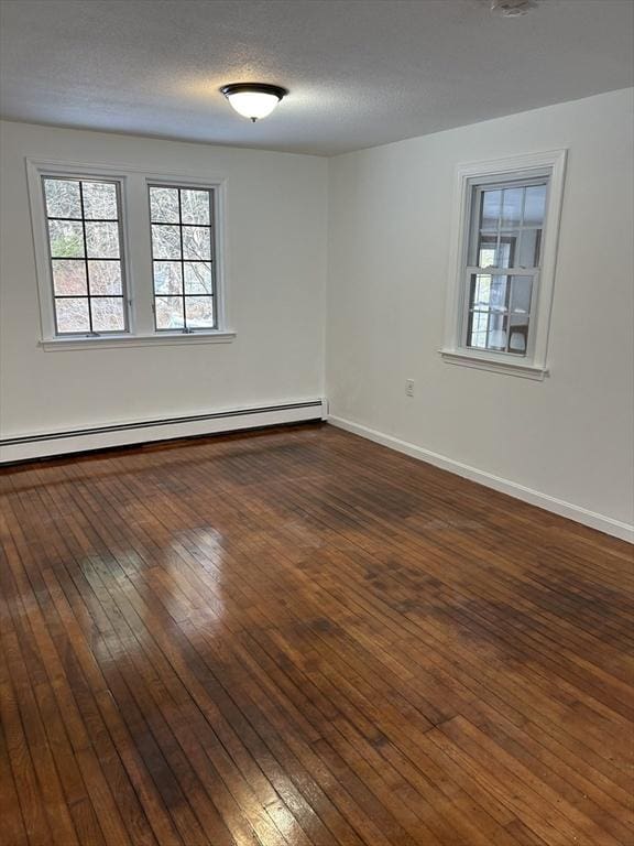 unfurnished room featuring a textured ceiling, dark hardwood / wood-style floors, and a baseboard heating unit