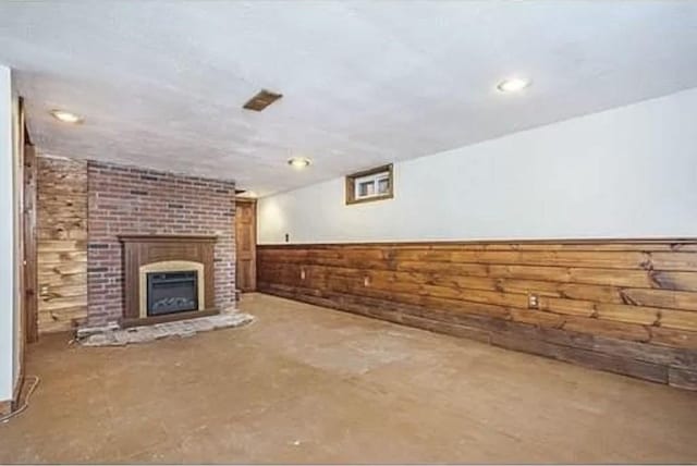 unfurnished living room featuring a fireplace and wood walls