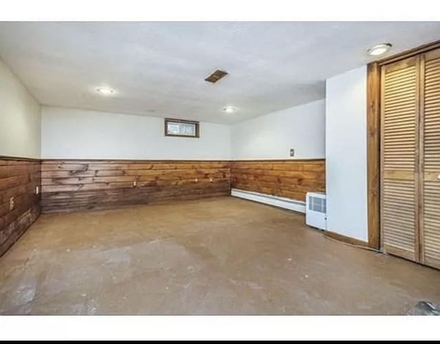 basement with wood walls and baseboard heating