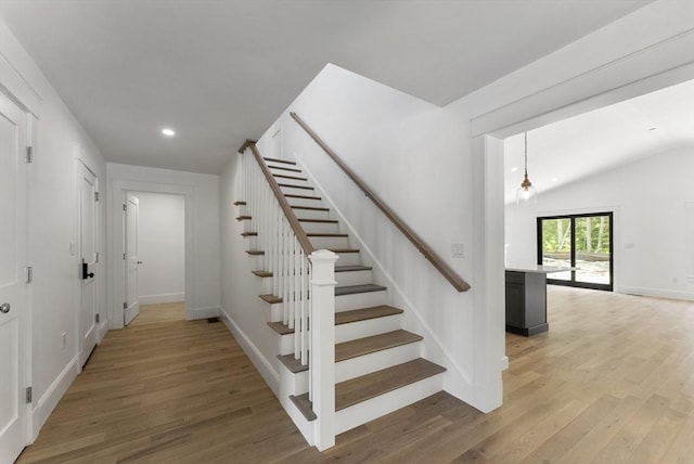 staircase with wood-type flooring and vaulted ceiling